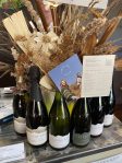 Cloudy Bay wine bottles with dried floral decor and Cloudy Bay Circle promotional card on display.